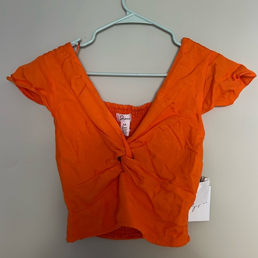 orange cropped top with capped sleeves and knot at the center chest